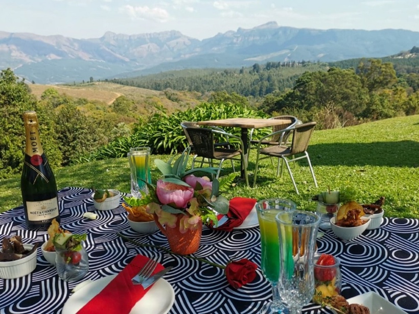 Alfresco lawn dining with champagne, colorful cocktails, small plates and flowers overlooking rolling hills and mountains.