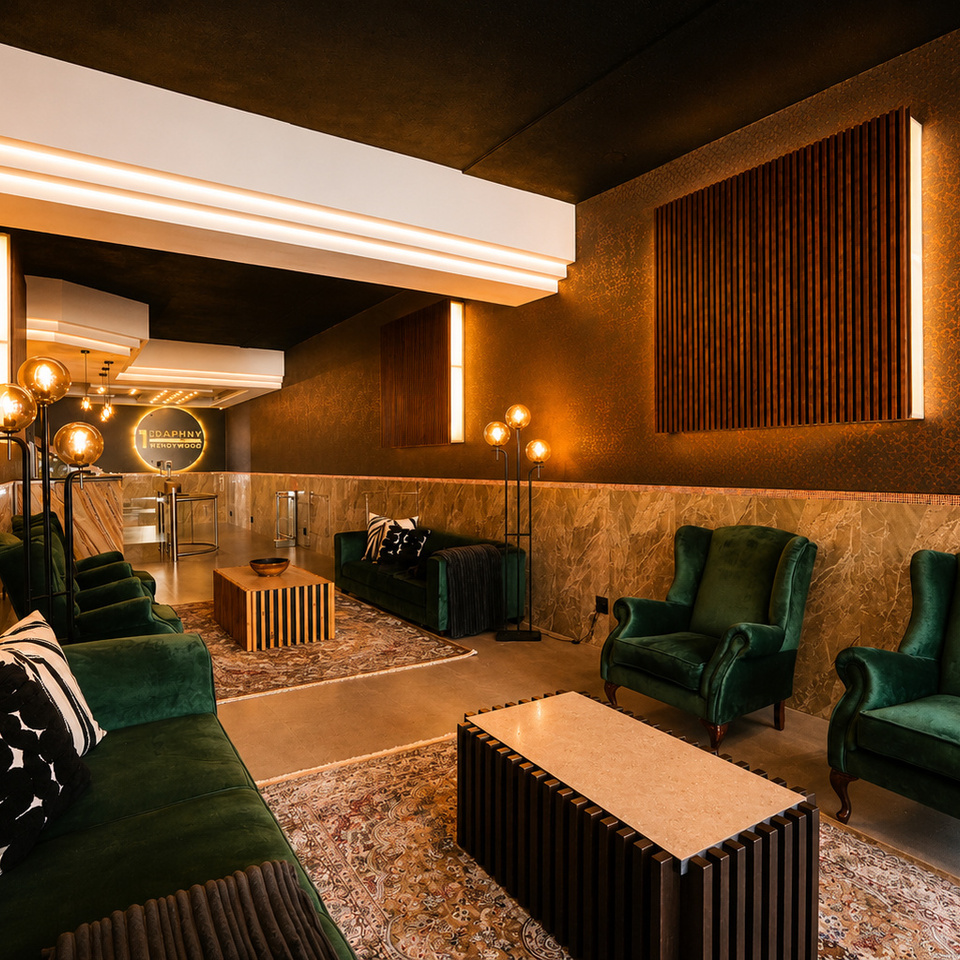 Intimate hotel lounge with emerald velvet sofas, armchairs, slatted wood coffee tables, globe lamps, marble walls and warm lighting