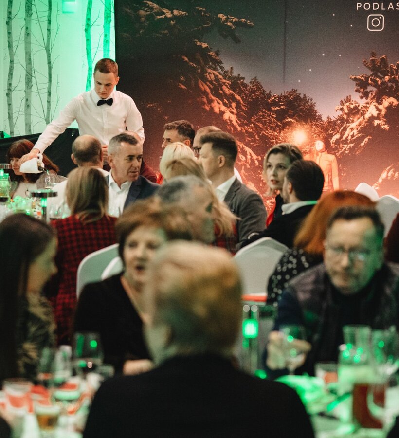 Elegant banquet hall event with guests seated at tables and a waiter serving drinks