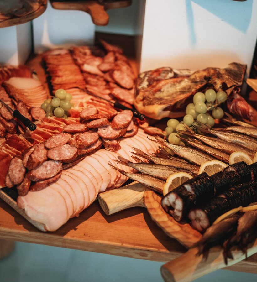 Table featuring smoked fish, assorted cold cuts, and grapes, perfect for a traditional hotel buffet spread.