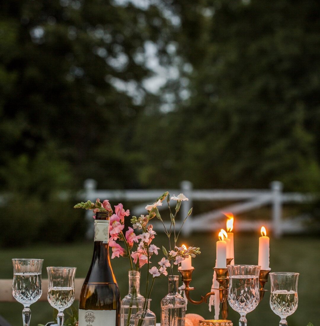 Romantyczna kolacja w ogrodzie. Białe wino, kieliszki do wina, kwiaty. Zaręczyny w ogrodzie.