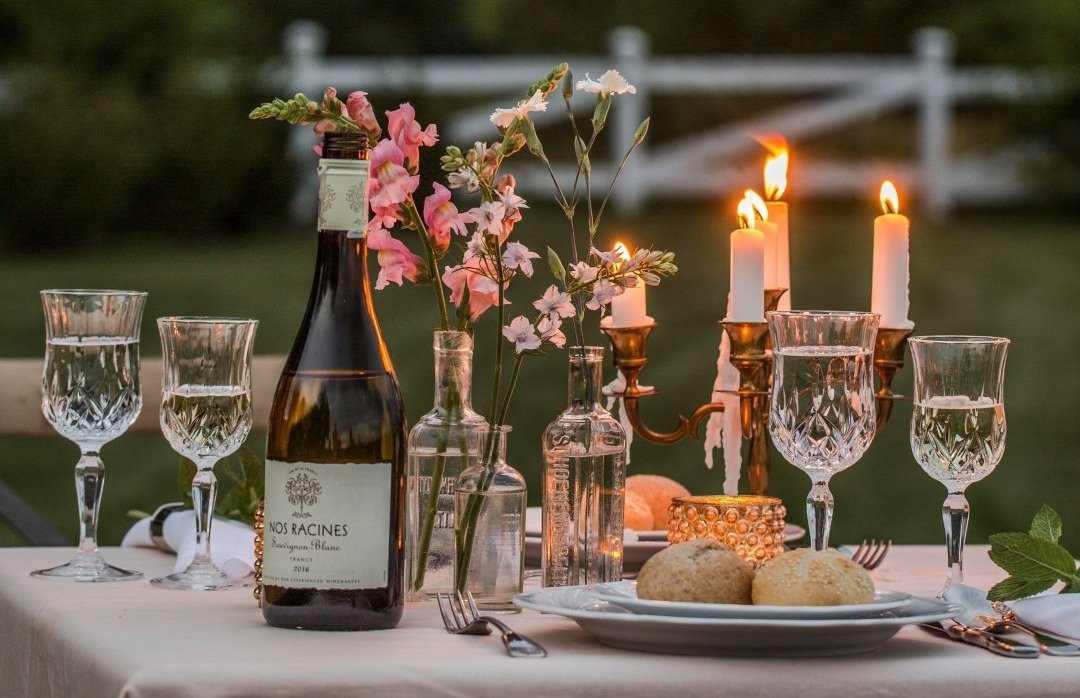 Romantic dinner in the garden. White wine, wine glasses, flowers. Engagement in the garden