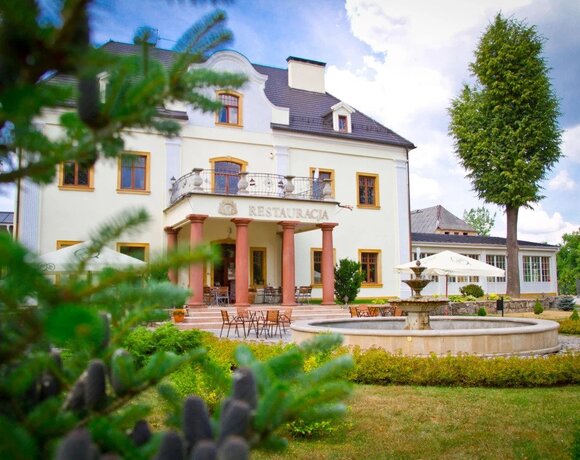 Pałacowy hotel z restauracją, kolumnowym portykiem, tarasem z kawowymi stolikami, ozdobną fontanną i zielonym ogrodem