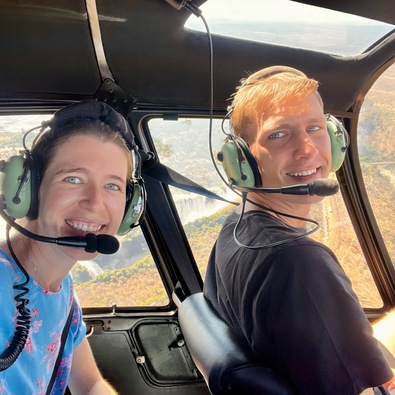 Paar genießt eine landschaftliche Hubschrauberrundfahrt mit Headsets und Blick auf Fluss und Wasserfall