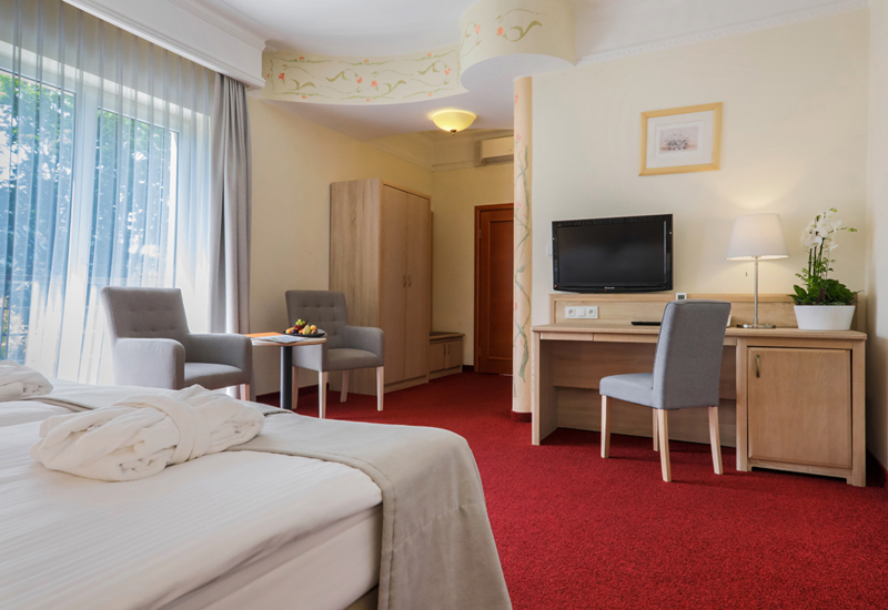 Jasne pomieszczenie pokoju Komfort z dużym oknem i kilkoma nowoczesnymi meblami