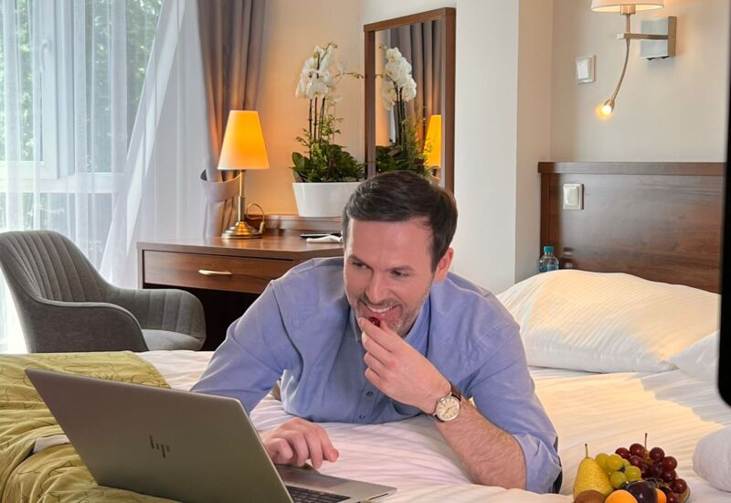 Mężczyzna w eleganckim stroju relaksujący się w hotelowym pokoju przeglądając oferty