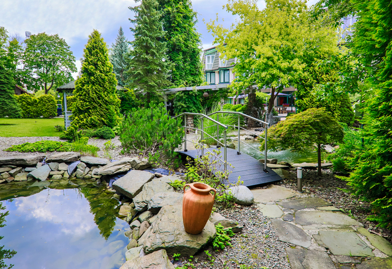 Taras i ogród z oczkiem wodnym i kładką, widok na hotel Papuga