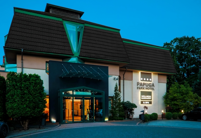 Oświetlony budynek hotelu Papuga Park wieczorem, widok od strony wejścia
