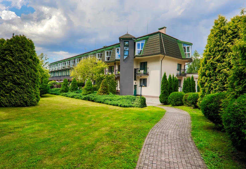 Zewnętrzny widok hotelu w otoczeniu ogrodu i zieleni