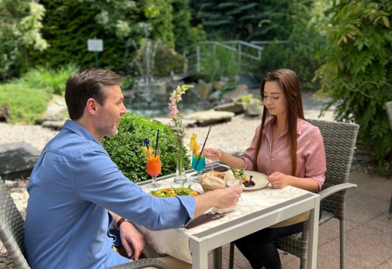 Radosna para podczas posiłku na tarasie z widokiem przy hotelu Papuga Park