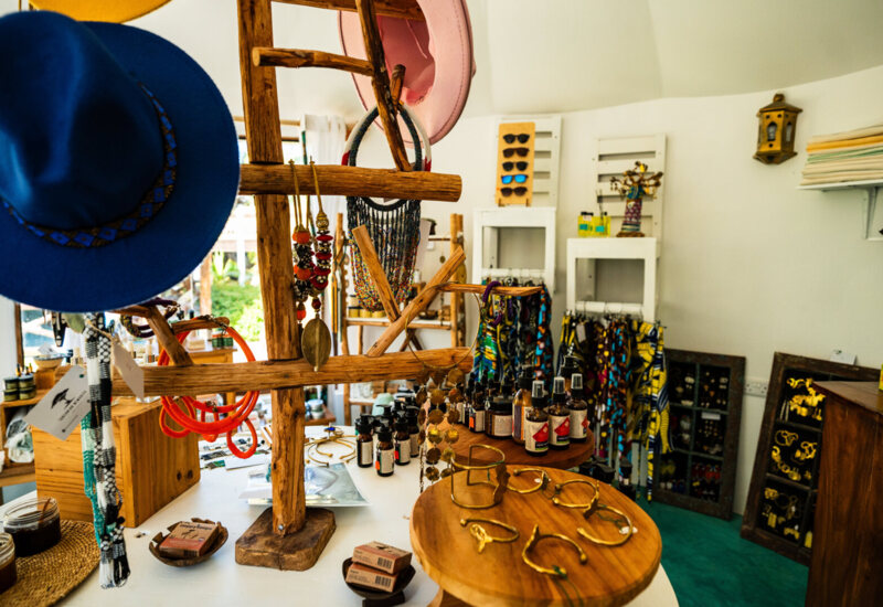 Boutique shop corner with colorful hats, handcrafted jewelry, natural skincare products, and vibrant accessories displayed on wooden racks