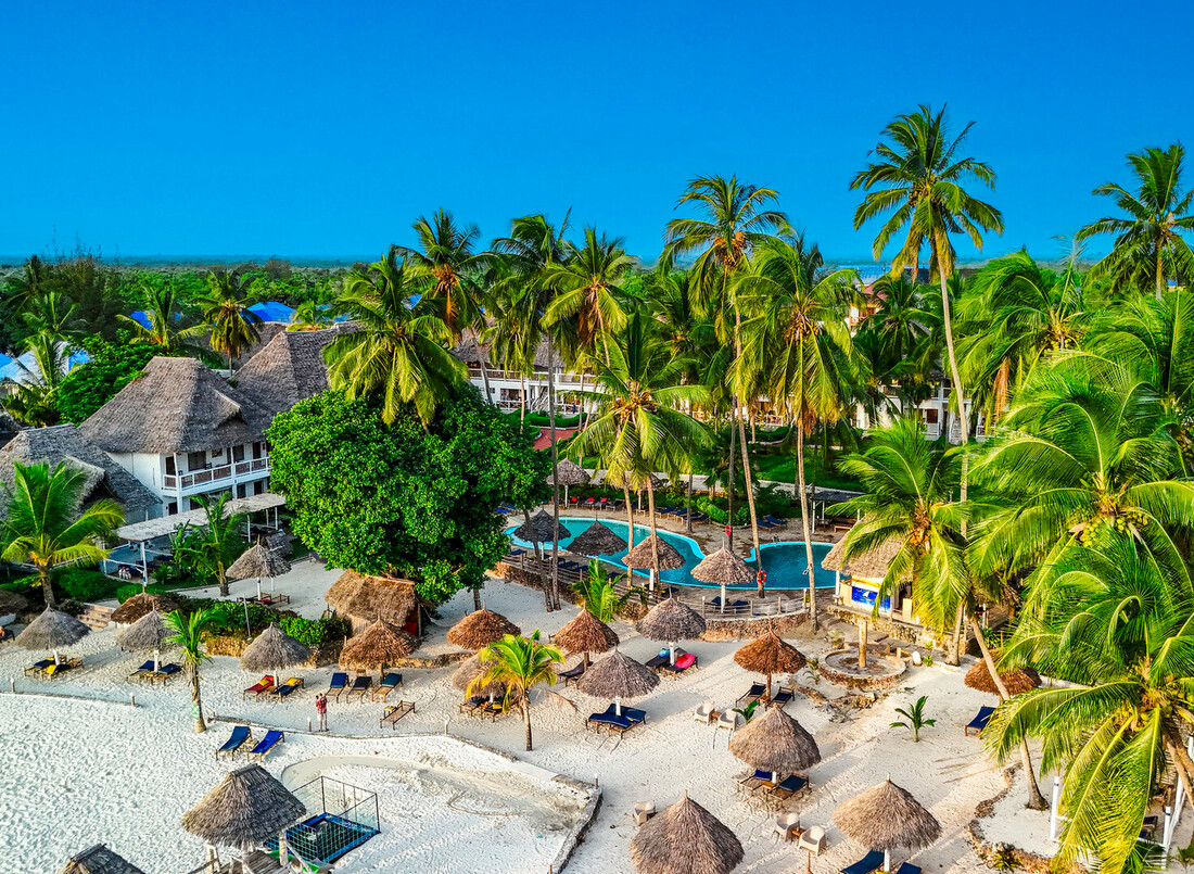 Tropical beachfront resort with white-sand beach, palm-shaded palapas, sun loungers, thatched villas and lagoon pool.