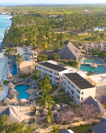 Beachfront resort with turquoise sea and white sand, palm-lined grounds, thatched-roof pavilions, pools and balcony rooms.
