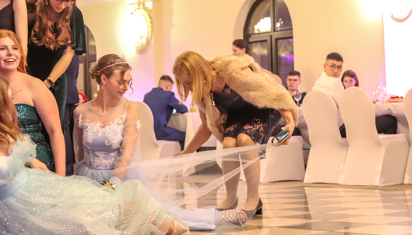 Elegantní společenská síň s hosty v večerních šatech na slavnostní akci v hotelu