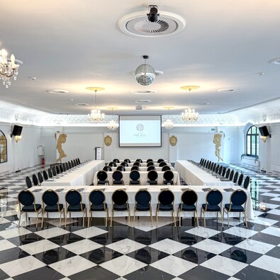 Elegant hotel conference room with white tablecloths, navy chairs, and glossy black-and-white marble floor.