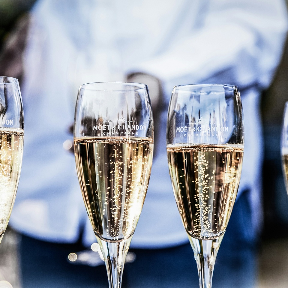 Kieliszki Moët & Chandon z musującym szampanem i złotymi bąbelkami, serwowane podczas eleganckiego toastu.