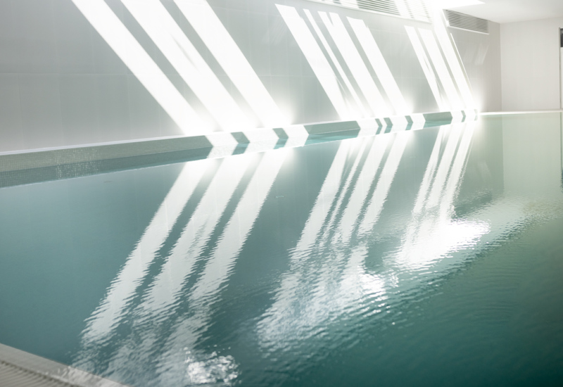 Jasny, nowoczesny kryty basen hotelowy z refleksami światła na spokojnej, czystej wodzie