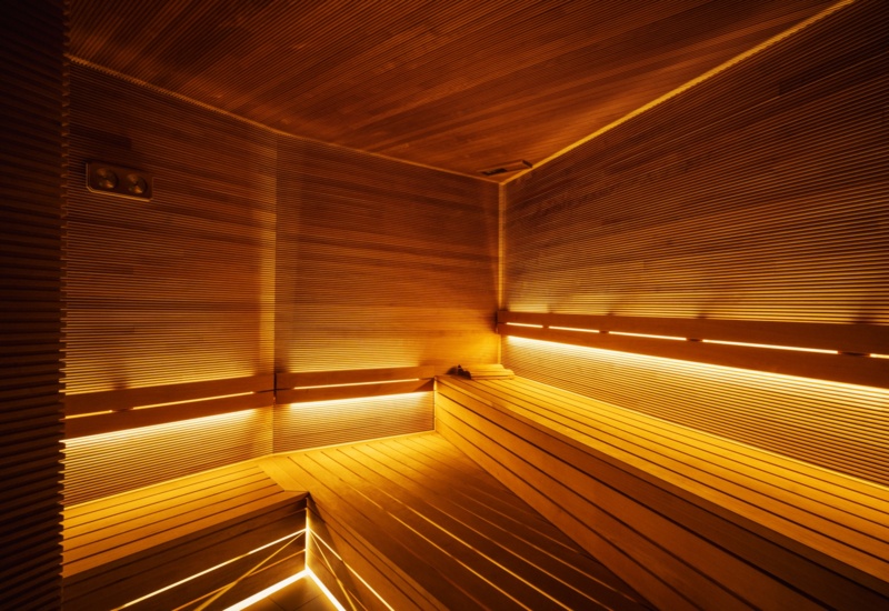 Nowoczesna sauna hotelowa z drewnianymi ławkami i ciepłym, nastrojowym oświetleniem LED