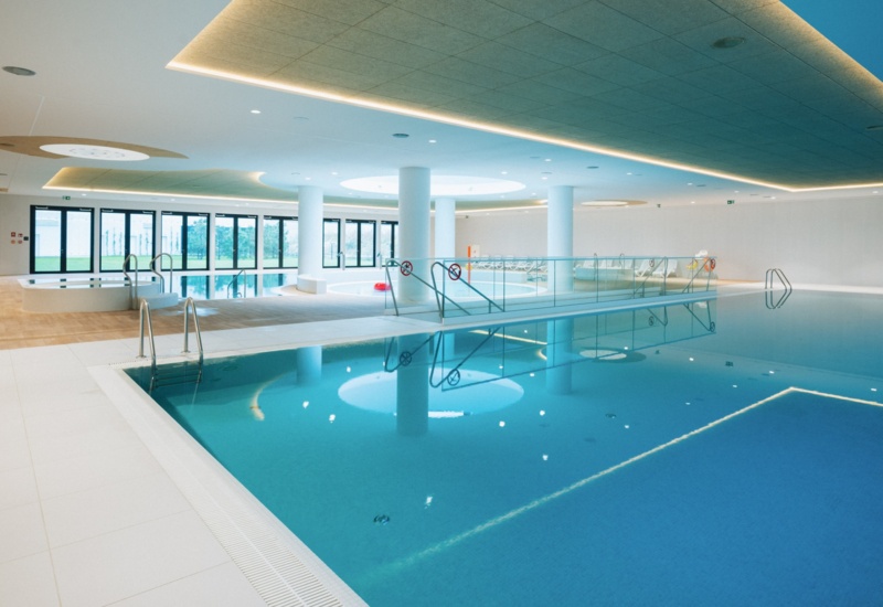 Przestronny, nowoczesny kryty basen hotelowy z dużą ilością naturalnego światła i relaksującą atmosferą.