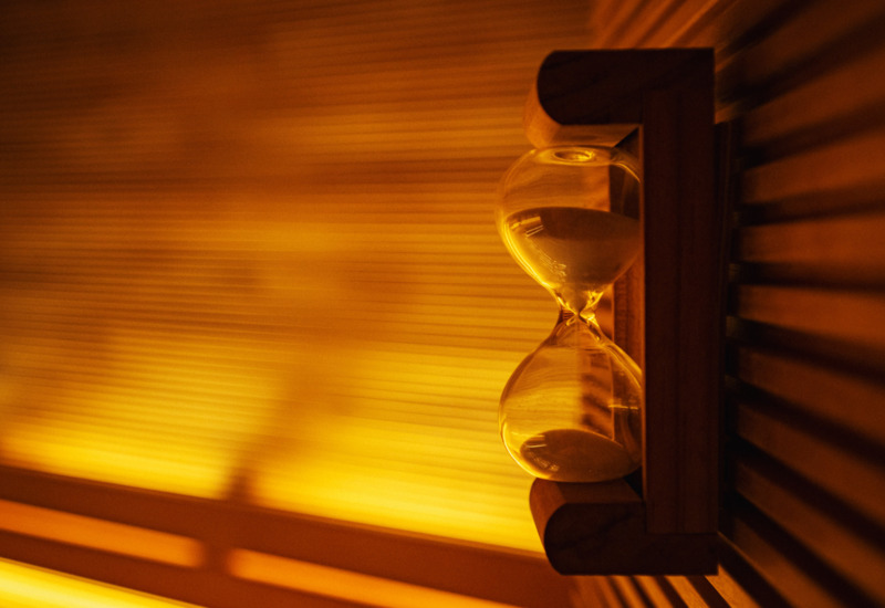 Klepsydra na drewnianej półce w saunie, ciepłe pomarańczowe światło tworzy relaksującą atmosferę