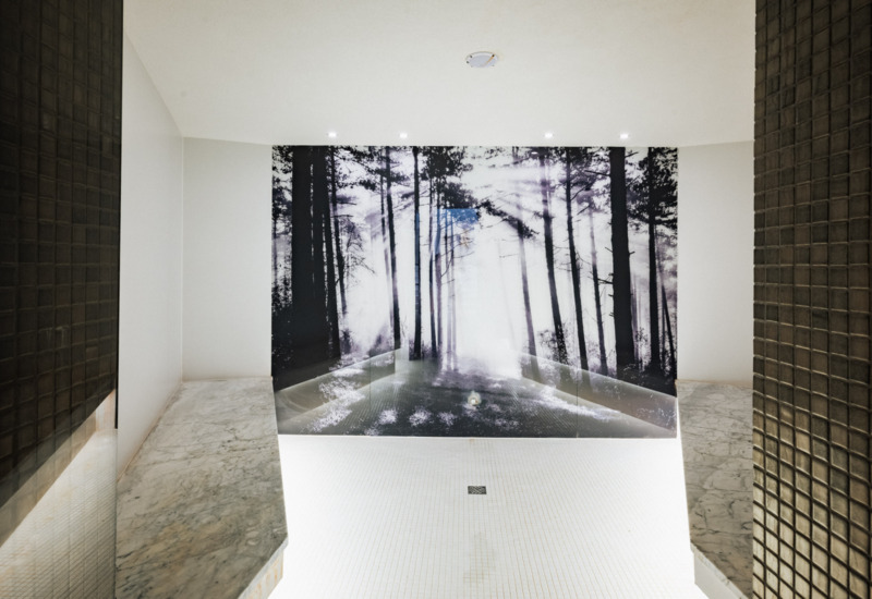 Nowoczesna łazienka spa z białą marmurową ławką i dużym czarno-białym muralem lasu w tle