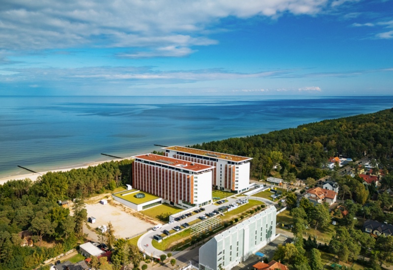 Nowoczesny hotel nad morzem z dużym kompleksem i widokiem na plażę otoczony lasem sosnowym