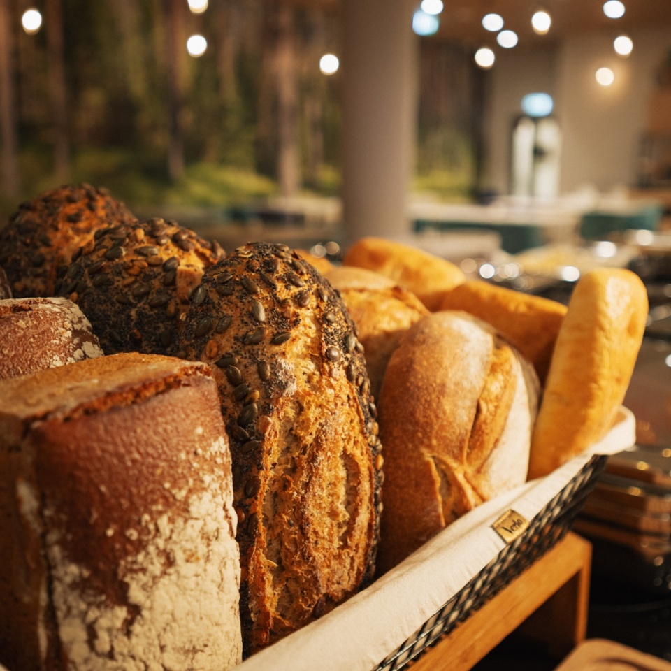 Świeże pieczywo z różnymi ziarnami serwowane w hotelowym bufecie śniadaniowym o przytulnej atmosferze.