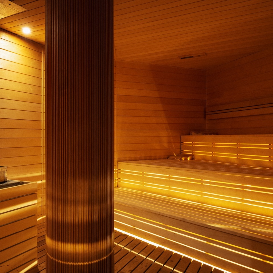 Nowoczesna sauna hotelowa z drewnianymi ławkami i nastrojowym oświetleniem dla relaksu gości