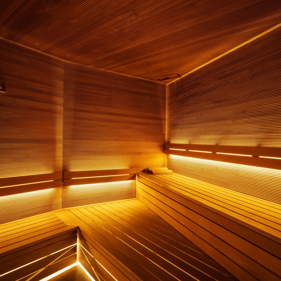 Nowoczesna sauna hotelowa z drewnianymi ławkami i ciepłym, nastrojowym oświetleniem LED