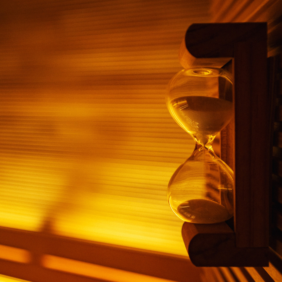 Klepsydra na drewnianej półce w saunie, ciepłe pomarańczowe światło tworzy relaksującą atmosferę