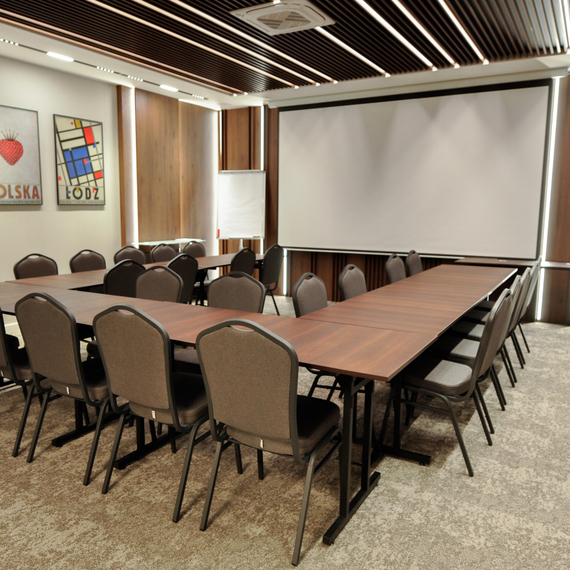 Modern conference room with tables arranged in a U shape, comfortable chairs, a projector and stylish wall décor