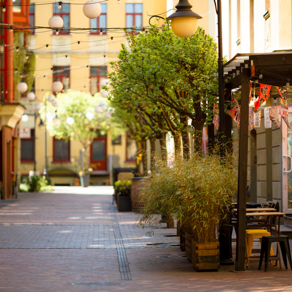 Street with an outdoor restaurant, decorated with green trees and lanterns, creating a pleasant atmosphere for relaxation