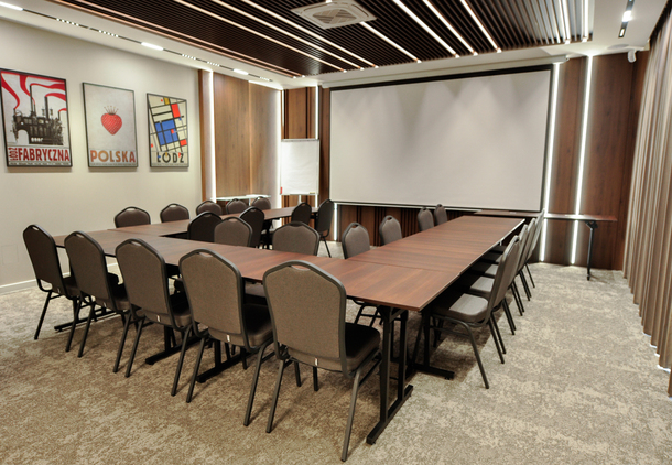 Modern conference room with U-shaped table setup, comfortable chairs, projector screen, and stylish wall art