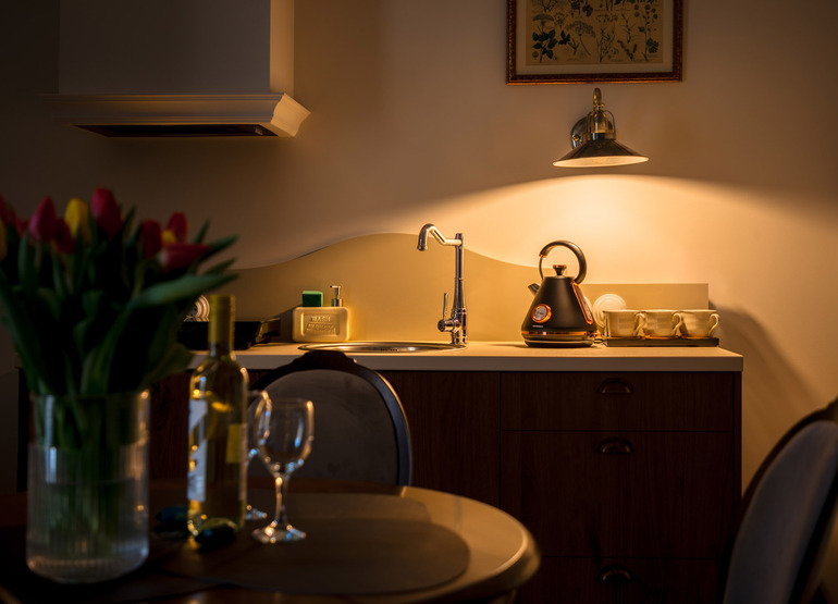 Kuchnia hotelowa z nowoczesnym czajnikiem, filiżankami, zlewem i nastrojowym oświetleniem, bukiet tulipanów i wino na stole