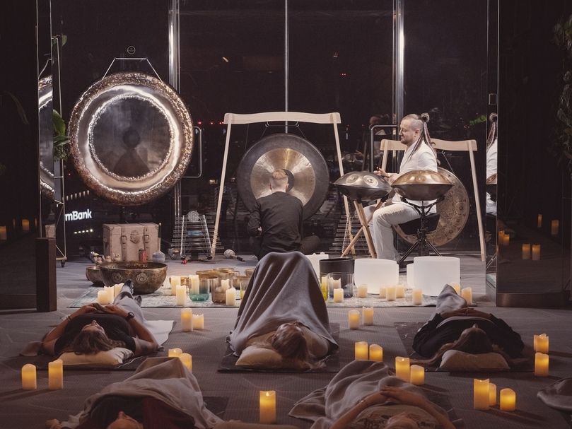 Gäste liegen auf Matten im Kerzenlicht bei einer Hotel-Soundbath-Session mit Gongs und Handpans.