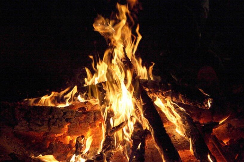 Outdoor crackling fire pit with stacked logs casting warm glow for cozy evening gatherings