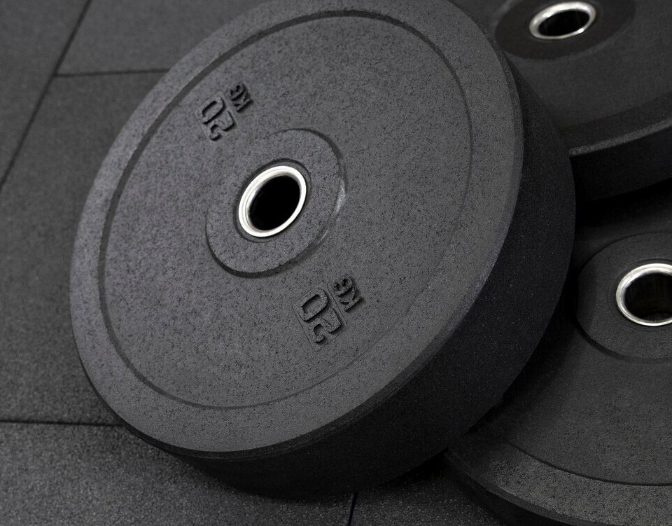 Black 20 kg bumper weight plates stacked on rubber gym flooring