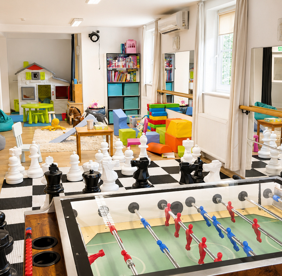 Bright family playroom with foosball table, oversized chess on checker rug, bean bags, toy house, colorful soft blocks and bookshelves