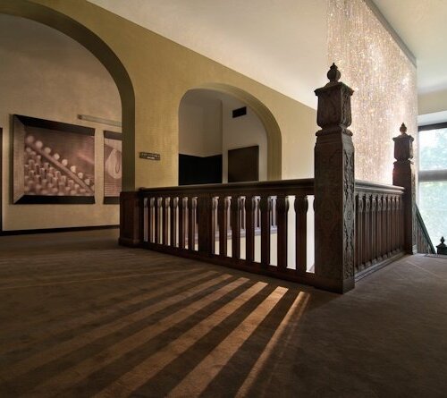 Historyczne lobby na piętrze z rzeźbioną balustradą, kurtyną z kryształów, łukowymi korytarzami i dużym oknem