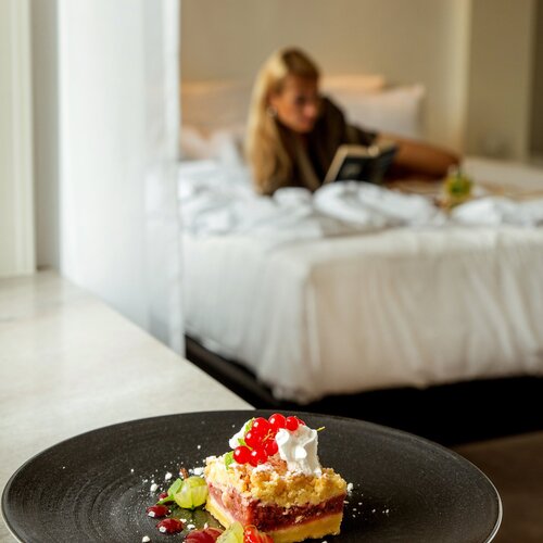 검은 접시에 담긴 과일 크럼블과 크림·베리, 침대에서 책 읽는 투숙객 옆에 룸서비스로 제공