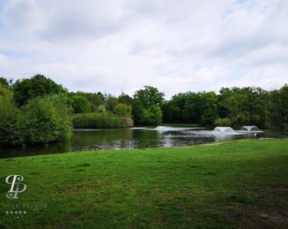 잔디가 있는 호숫가, 두 개의 분수와 나무로 둘러싸인 수변, 물가에 있는 사람