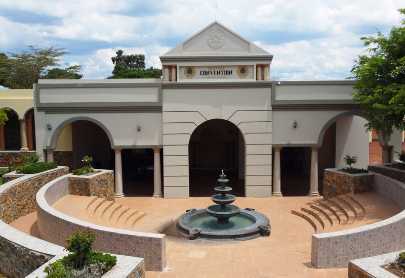 Grand convention center with classical arches and columns, tiered fountain, curved stone terraces and stepped seating.