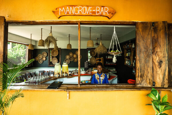 Bright Mangrove Bar with rustic wooden window, hanging woven lamps, tropical decor, and friendly staff behind the counter
