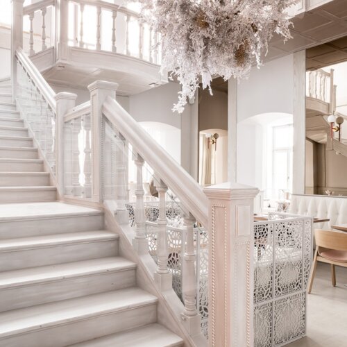 Widok na białe schody i okazały żyrandol.