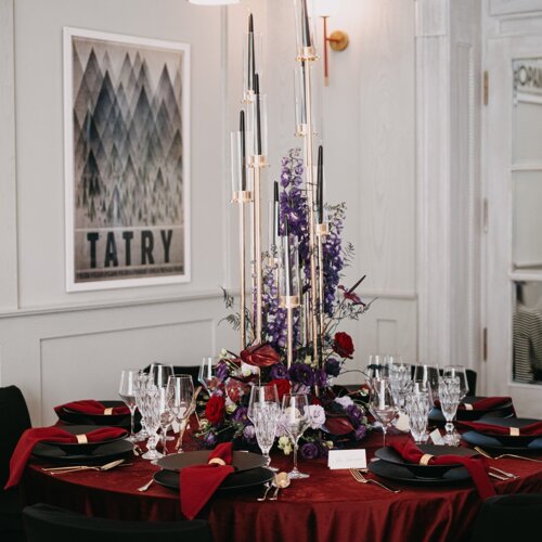 Stół udekorowany w ciemnym czerwonym kolorze.