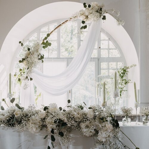 Ślubnie udekorowany stół na tle okna.