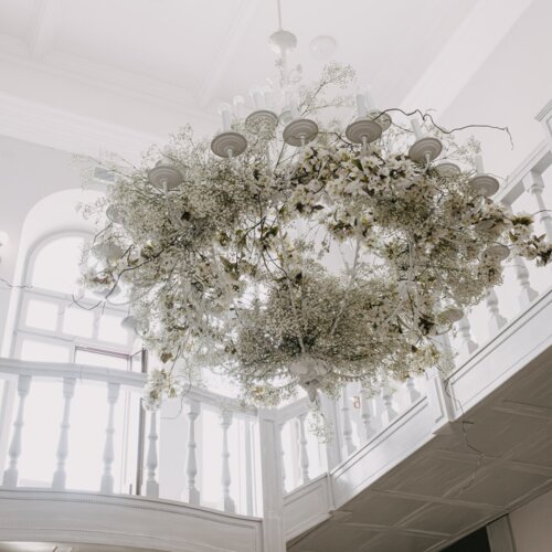 Widok z dołu na żyrandol udekorowany białymi kwiatami.