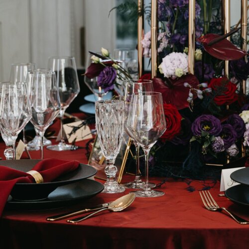 Kieliszki na stole z ciemnoczerwoną serwetą.