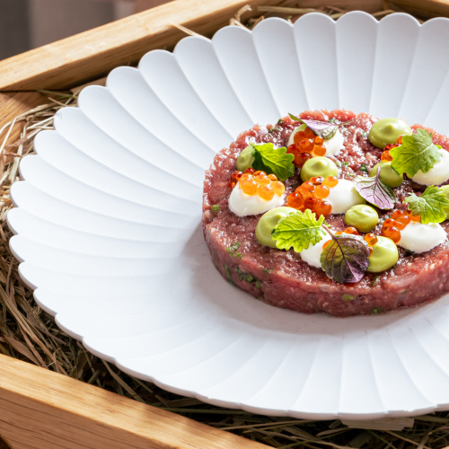 Tatar z warzywami na dużym białym talerzu.