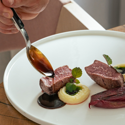 Kawałki mięsa na talerzu polewane sosem